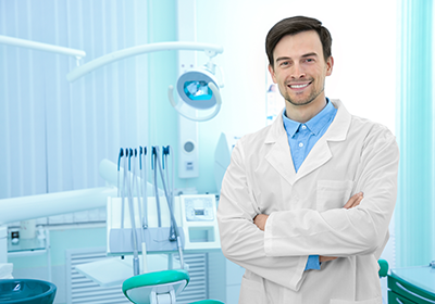 male-dentist-with-arms-crossed-in-exam-room - Fort Dental Health Group